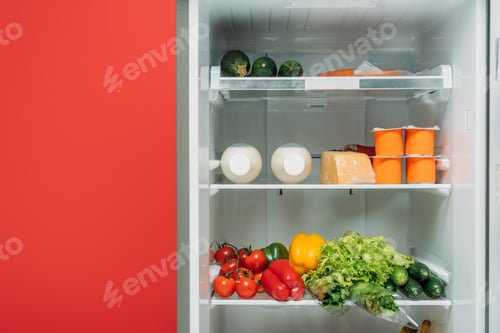Preview: open fridge full of fresh food on shelves isolated on red