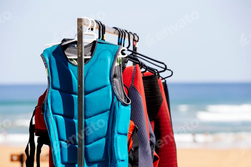 Preview: A row of wetsuits hanging on a rack at a surf school.