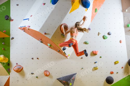 Preview: Young woman jumping on handhold in bouldering gym
