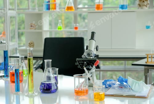 Preview: The microscope is put on desk with various glassware of science working.