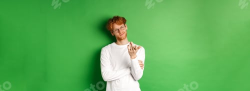 Preview: Young man with red messy hair and glasses, smiling pleased and pointing hand at camera, your turn