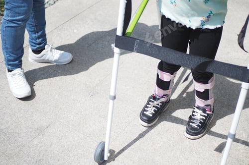 Preview: child with walking frame and knee orthosis outdoor