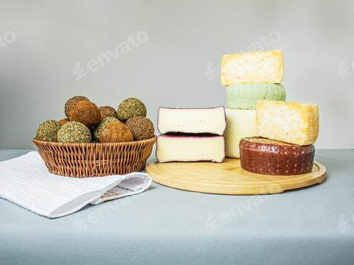 Preview: hard and semi-hard cheeses on a wooden cutting board and a cheese knife on a gray background, caciot