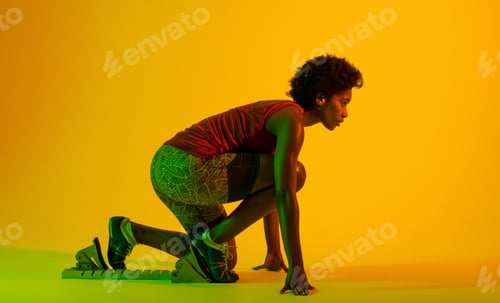 Preview: Image of african american female athlete preparing for run in yellow lighting