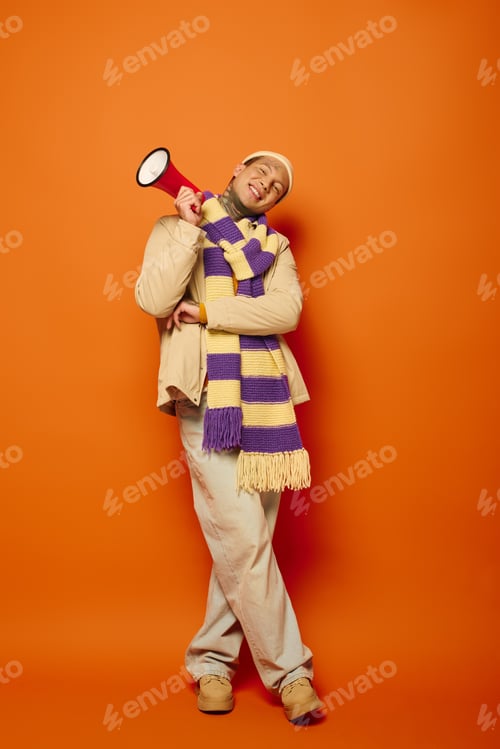 Preview: Young man in colorful scarf holds a megaphone against a vibrant orange backdrop