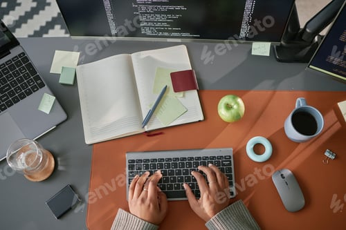 Preview: Young Adult Woman Typing Code on Wireless Keyboard at Modern Office Desk