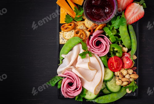 Preview: Antipasto platter cold sliced ham, salami, crackers, strawberries, vegetables and cheese platter
