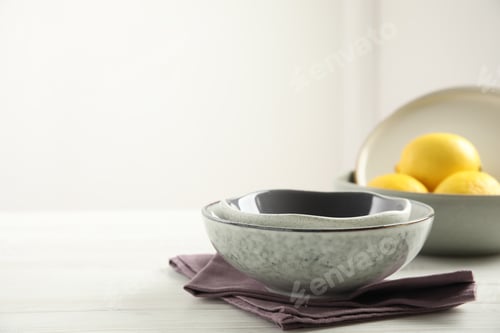 Preview: Set of clean dishware and lemons on white wooden table. Space for text