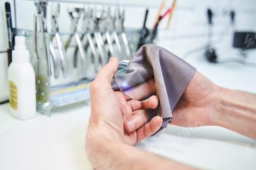 Preview: Male optician cleaning lens for eyeglasses in workshop