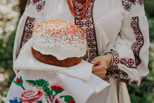 Preview: Ukrainian woman holding in hands Easter cake. Lady in embroidery vyshivanka dress on nature