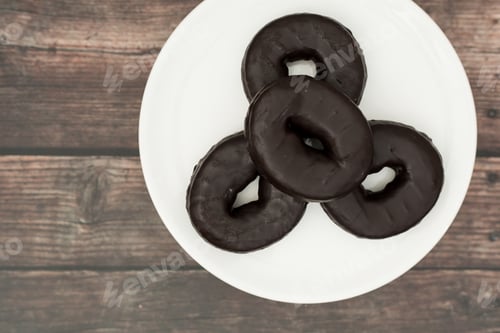 Preview: Top view of delicious chocolate donuts on a white serving plate