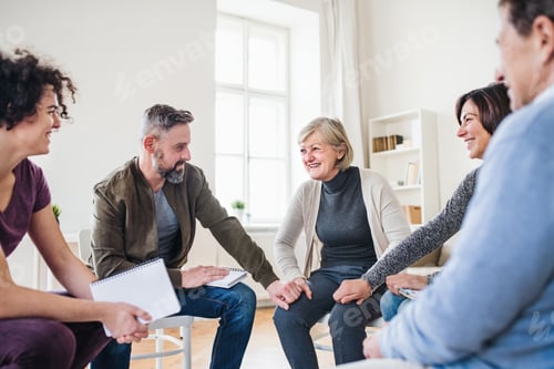 Preview: Men and women sitting in a circle and holding hands during group therapy.