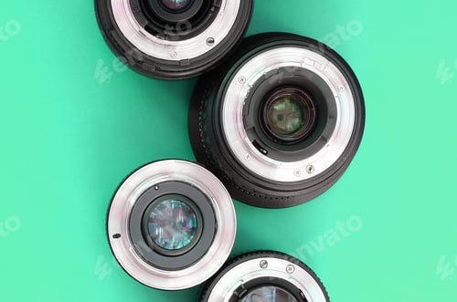 Preview: Several photographic lenses lie on a bright turquoise background. Copy space