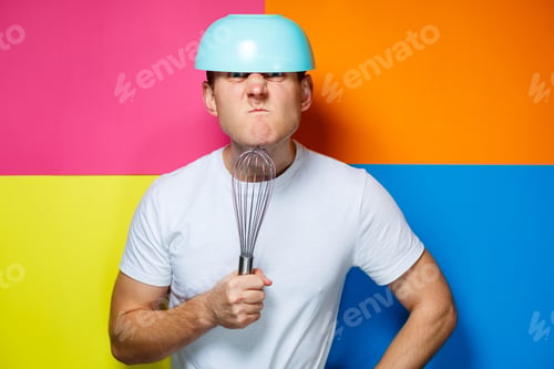 Preview: young guy man in a white T-shirt, colorful background, kitchen utensils, cook, emotions photo
