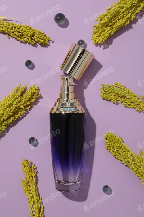Preview: Bottle with perfume and plants on purple background, top view