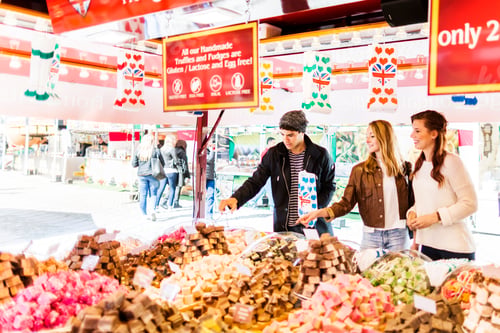 Preview: Friends picking out treats at a colorful market stall.