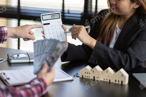Preview: Businesswoman or real estate agent discusses with customers about buying and selling house prices.