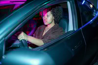 Preview: Young African female driving electric car while holding by steering wheel