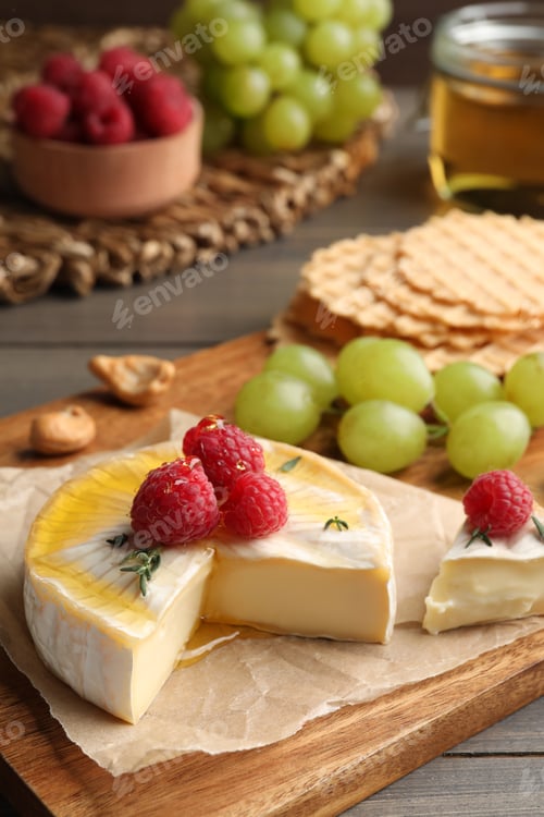 Preview: Brie cheese served with berries and honey on wooden table, closeup