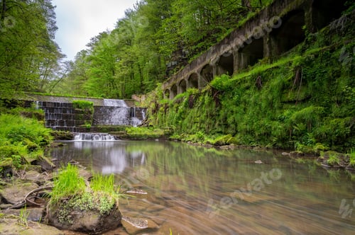 Preview: Picturesque waterfall cascading down a rocky cliff face surrounded by lush greenery