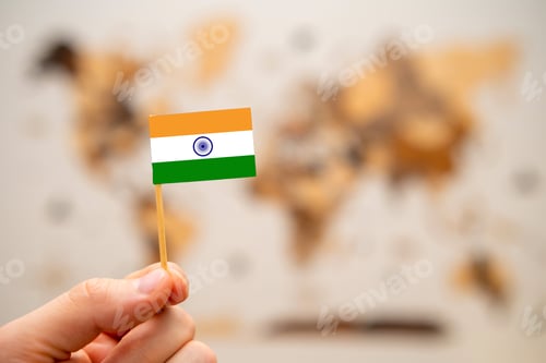 Preview: India flag in mans hand on the world map background.