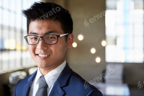 Preview: Young Asian businessman smiling to camera, head and shoulders