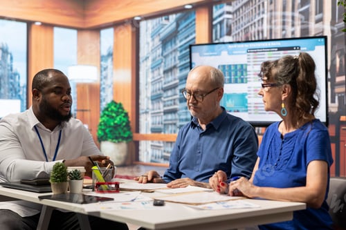 Preview: Mature couple in detailed discussion with financial expert about retirement plan