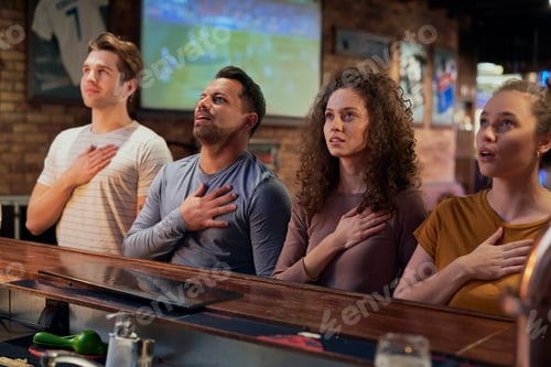 Preview: Group of friends singing national anthem in the pub