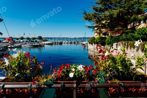 Preview: Boats moored next to Sirmione Castle on Lake Garda admired by tourists in summer.