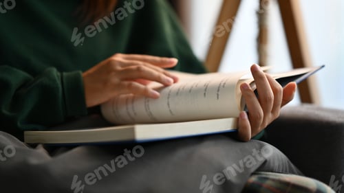 Preview: Young woman reading book while relaxing and enjoying favorite novel at home