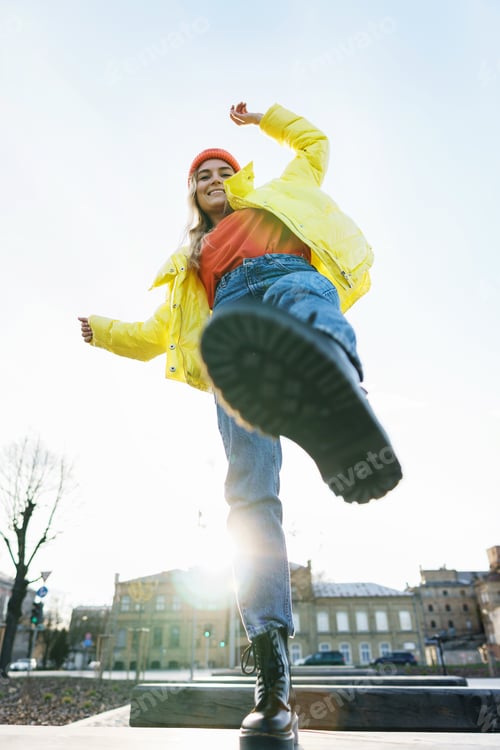 Preview: Stylish girl wearing yellow puffer and orange knitted hat