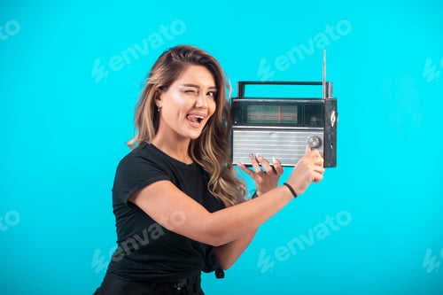 Preview: Young girl in black shirt holding a vintage radio and listening it