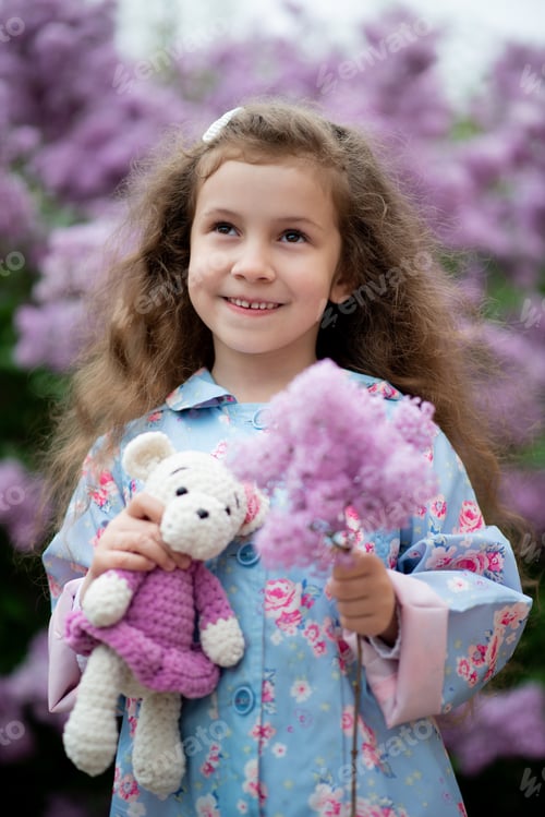 Preview: A cute girl next to a bush of blooming lilacs.