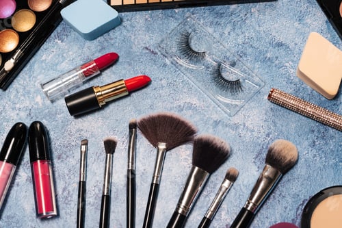 Preview: decorative cosmetics, makeup brushes false eyelashes on a blue background. the view from the top