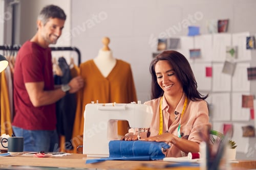 Preview: Female Fashion Designer Working On Sewing Machine As Male Colleague Works In Background