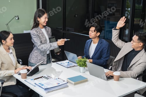 Preview: Asian businessman showing hand and smiling young team of colleagues making good business discussion