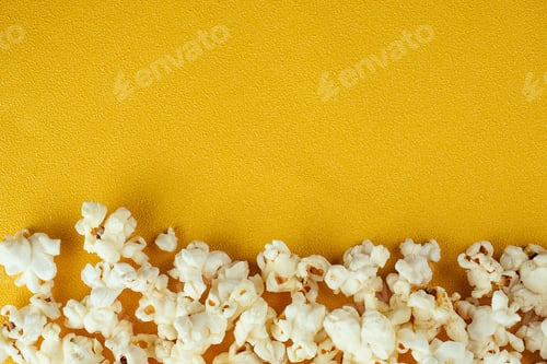 Preview: popcorn scattered from a paper striped cup on a yellow background.