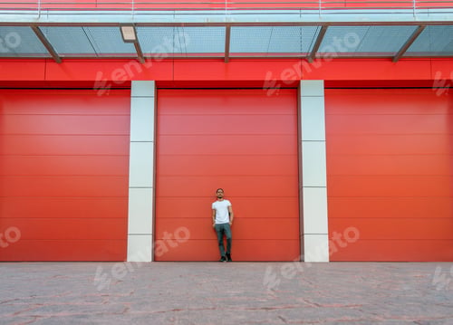 Preview: Man portrait leaning on a red warehouse door