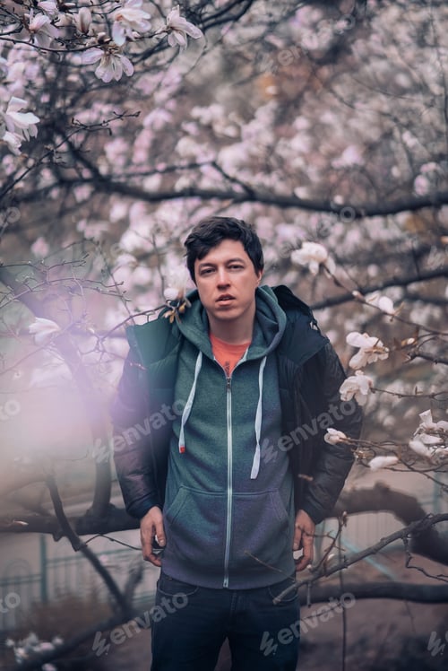 Preview: Handsome man near magnolia flowers, background defocused