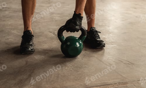 Preview: Crop sportsman lifting kettlebell from floor