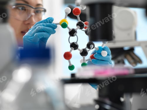 Preview: Scientist designing drug formula using ball and stick molecular model in laboratory