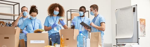 Preview: Full length shot of volunteers in protective masks and gloves sorting, packing food and water