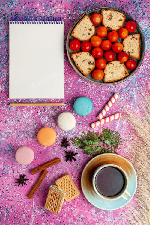 Preview: top distant view delicious sliced cake with sour fresh plums french macarons and cup of tea on the