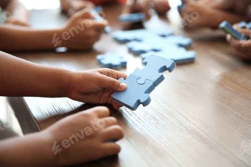 Preview: Little children playing with puzzle at table, focus on hands. Unity concept