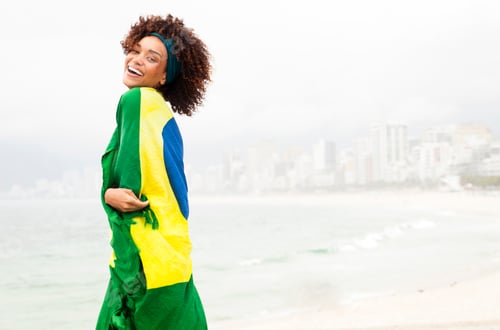 Preview: Portrait of young woman wrapped in Brazilian flag on Ipanema beach, Rio De Janeiro, Brazil