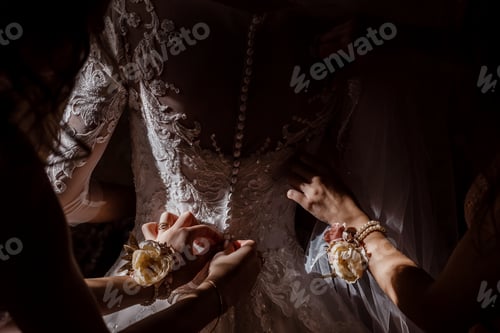 Preview: Bridesmaid helping bride fasten corset and getting her dress, preparing bride in morning for