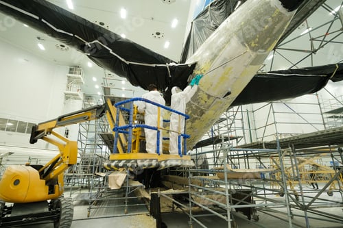 Preview: Maintenance work on aircraft tail section inside a large hangar with workers