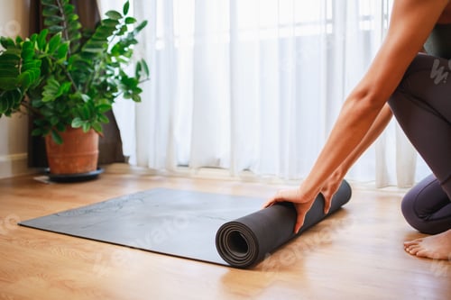 Preview: Close-up of woman hands unrolling roll black yoga mat for playing yoga at home