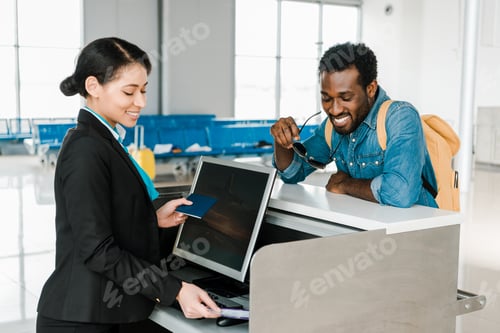 Preview: smiling african american airport worker checking air ticket and passport at ticket control in
