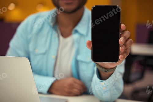 Preview: Young man showing smartphone in the office